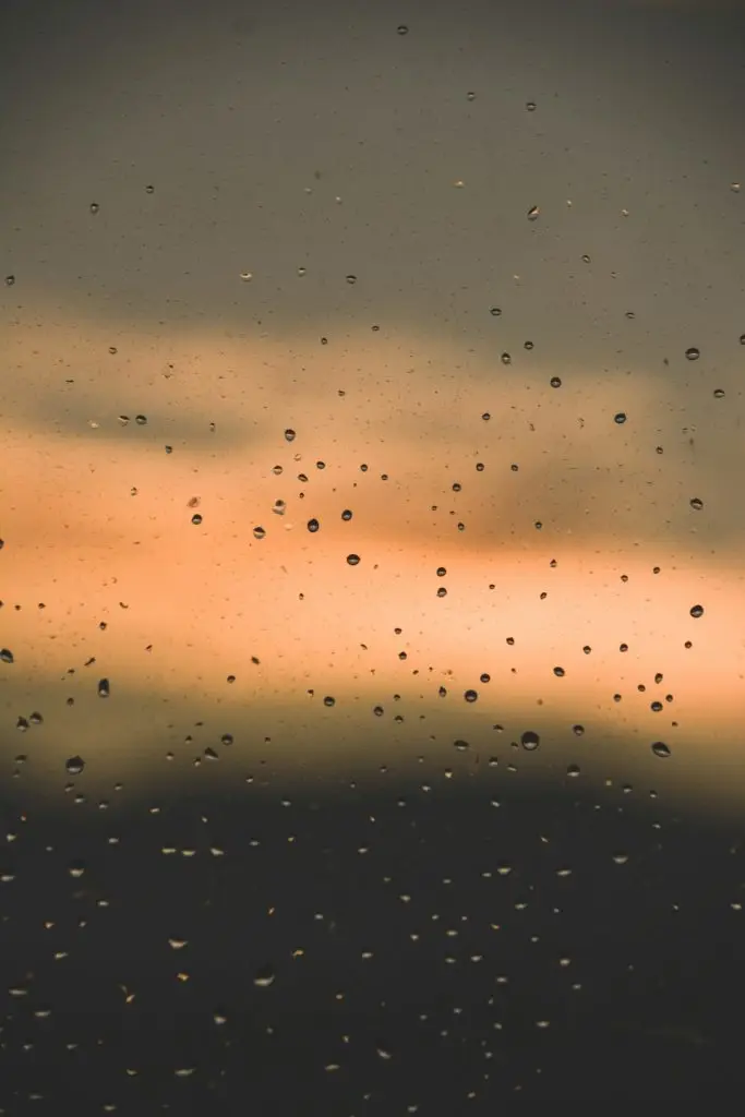 rain-drops-on-a-window-with-a-sunset-in-the-background-tllslmx3i1m